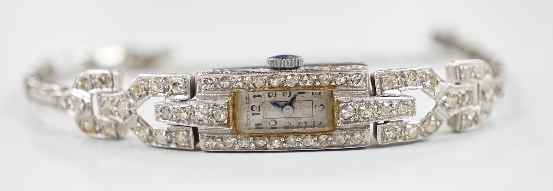 A lady's platine and diamond cluster set manual wind cocktail watch, with rectangular Arabic dial, on a white metal expanding bracelet, 16cm, gross weight 15 grams.